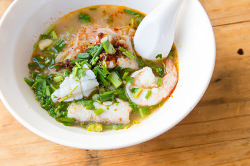 bowl of noodles with vegetables on wooden table.