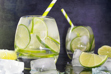 Detox water with lime and ice on a dark background.
