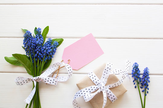 Beautiful Blue Flowers Of Muscari And Gifts On A White Wooden Table Top View