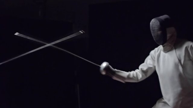 Two professional fencers competing with foils while practicing fencing skills. Slow motion