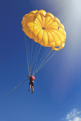 Skydiver on yellow parachute in sunny blue sky. Active lifestyle. Extreme sport.