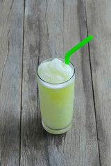 Green Apple juice in glass on wooden table floor.