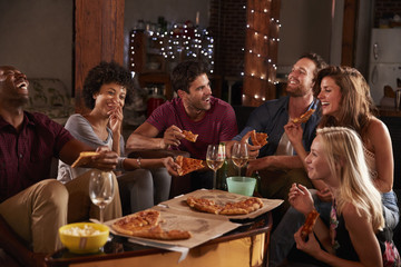 Young adults sharing pizzas at a party at home