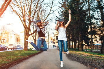 Fototapeta premium Two pretty girls enjoy virtual reality glasses outdoor