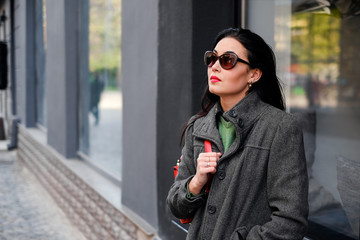 brunette girl walking on the street with red backpack