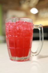 Red soda drink in glass on the food table.