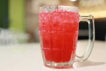 Red soda drink in glass on the food table.