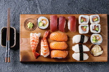 Sushi Set nigiri et sushi rolls sur planche de service en bois avec sauce soja et baguettes sur fond de texture de pierre noire. Vue de dessus avec espace. Menu Japon