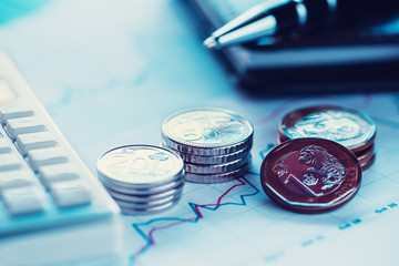 Closeup coins on line chart with pen and calculator