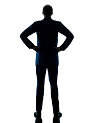 one caucasian business man standing rear view silhouette isolated on white background