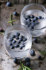 Tonic water cocktail with rosemary, blueberries. Two cold glasses over over dark texture metal background. Refreshing beverage alco non alcohol