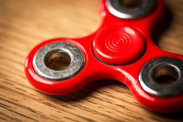 Red spinner gadget over wooden table.