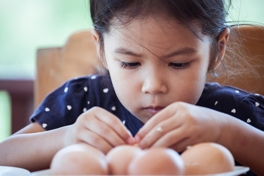 Asian little girl helping mother to peel egg