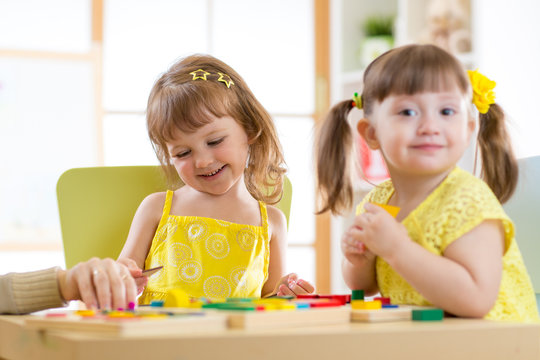 Kids children girls playing with educational child toys at home or daycare centre.