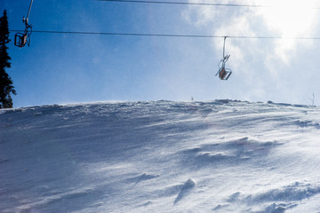 Fototapeta na wymiar Wind blowing snow near lonely ski lift