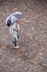 femme marchant avec un parapluie sur un place pavée