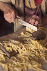 Elderly woman cutting pasta