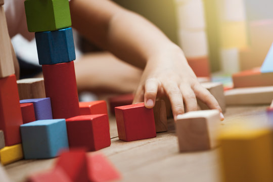 Focus on child's hand  playing with colorful wooden blocks in vintage color tone