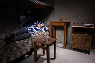 Young woman prisoner wearing prison uniform has lost in thought while lying in bed