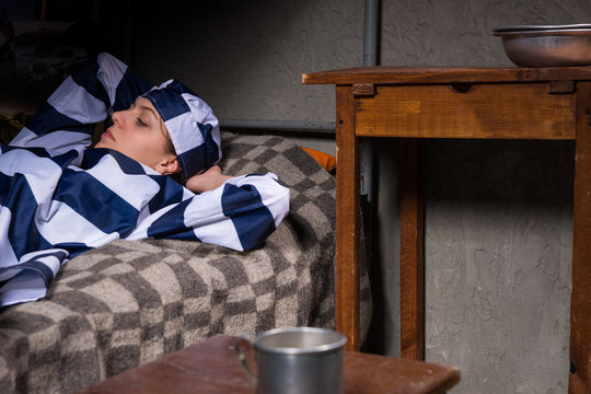 Portrait of female prisoner wearing prison uniform has lost in thought while lying in bed