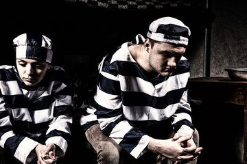 Young prisoner couple wearing prison uniform have lost in thoughts in a prison cell