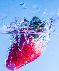 strawberry falling in water, leaving splashes and bubbles