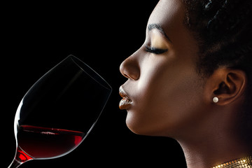 African woman smelling red wine aroma.