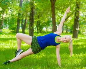 Fototapeta premium Happy girl doing side plank on green grass