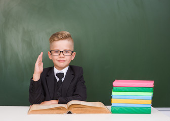 Young boy in a suit raising hand knowing the answer to the question
