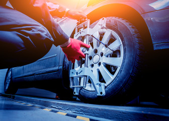 Car mechanic installing sensor during suspension adjustment.