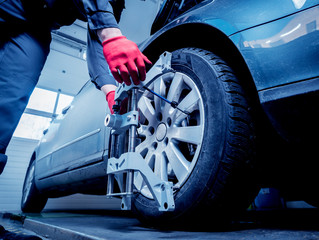 Car mechanic installing sensor during suspension adjustment.