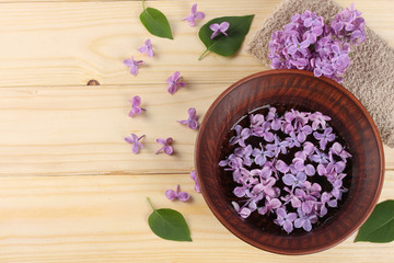 Fototapeta na wymiar lilac flower on light wooden background. top view