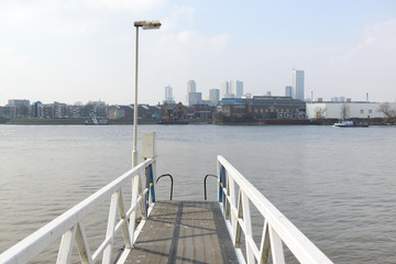 Pier over the Maas river with in the background the Feijenoord district and skyscrapers at downtown Rotterdam