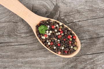 black pepper. peppercorns in wooden spoon on wooden background with copy space. top view