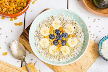 Healthy Paleo Raw Avocado Banana Smoothie Bowl with Almond Milk, Blueberry, Seeds, Coconut Flakes and Golden Raisins, Horizontal View