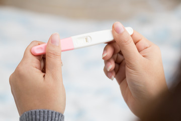 Woman hand holding pregnancy test and result is not pregnant - obrazy, fototapety, plakaty