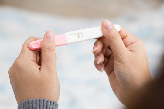 Woman hand holding pregnancy test and result is not pregnant