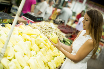 Young woman picking fresh vegetable at the market