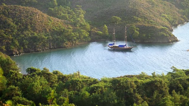 Beautiful nature of Mediterranean on the azure coast of Turkey. 4K. Bordubet - a shallow bay surrounded by pine tree forest. Typical Turkish style gulet yacht anchored in the bay