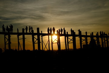 Silhouettes of people walking on long wooden bridges in the world in Burma