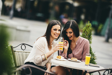 Portrait of beautiful young women eating cake at outdoors cafe
