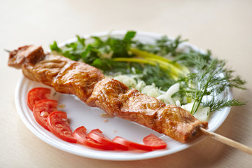 Grilled pork kebab with tomatoes, onion and greens on plate
