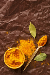 Curry powder in a bowl with laurel leaves and spoon viewed from above. Top view. Copy space