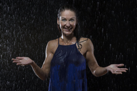 Beautiful woman in blue dress stands in rain at night