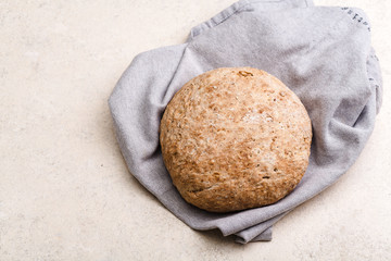 Loaf of homemade whole grain bread on towel on rustic background. Eco lifestyle concept. Copy space