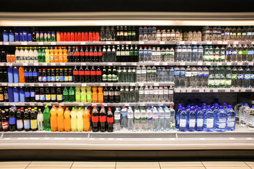 Different drinks in bottles on shelves of supermarket