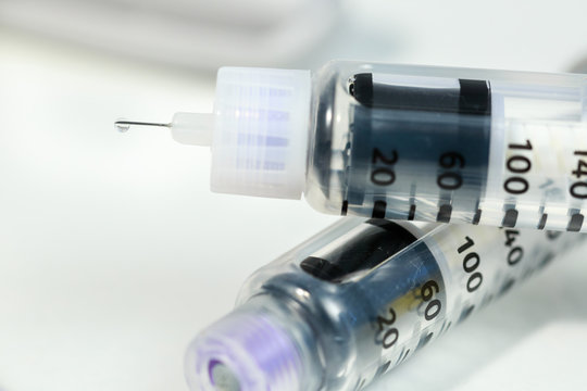 Empty insulin pens on white. Drop of insulin on the needle of one of them