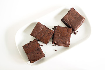 Sliced brownies on white plate over white background. Top view. Sweet and moist chocolate dessert.