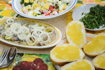 Spring salad with eggs, cucumbers and radishes, herring with onions and Sandwiches with pike caviar stand on the table. Useful and tasty lunch.