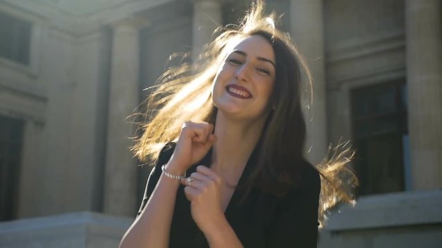 Young happy girl dancing and bouncing and jumping full of joy in the city in slow motion